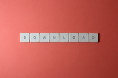 Buchstaben auf neutralem Hintergrund Weiße Tastenkappen bilden das Wort „DOWNLOAD“ auf korallenrotem Hintergrund, mittig und in einer Reihe angeordnet.