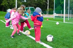 Kinder spielen Fußball Kinder spielen auf einem Fußballfeld: Mehrere Kinder mit Bällen üben Kicken nahe einem Tor auf grünem Rasen.